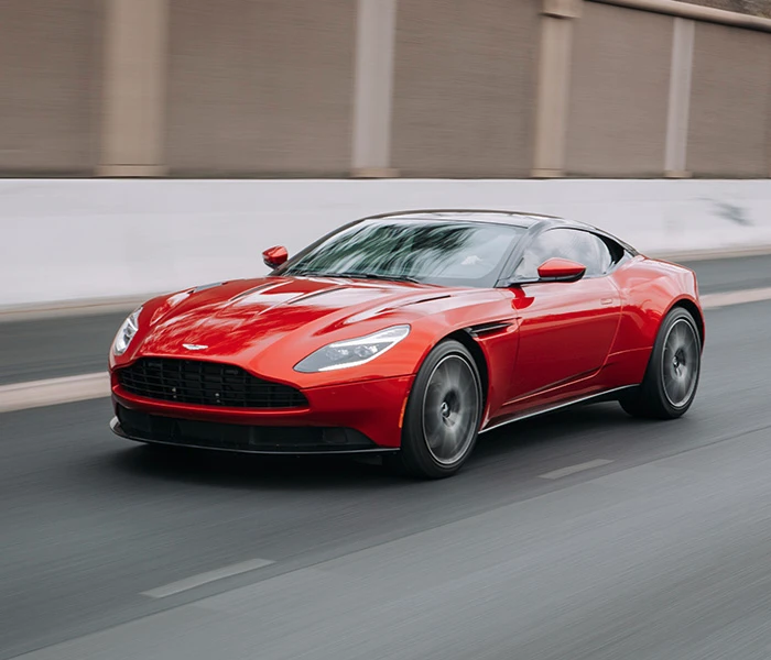 Red Aston Martin driving on the road