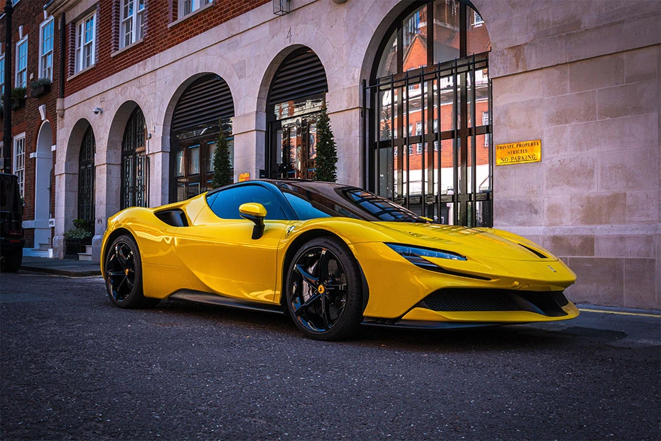 Yellow Ferrari SF90 Stradale parked on the road in front of a building