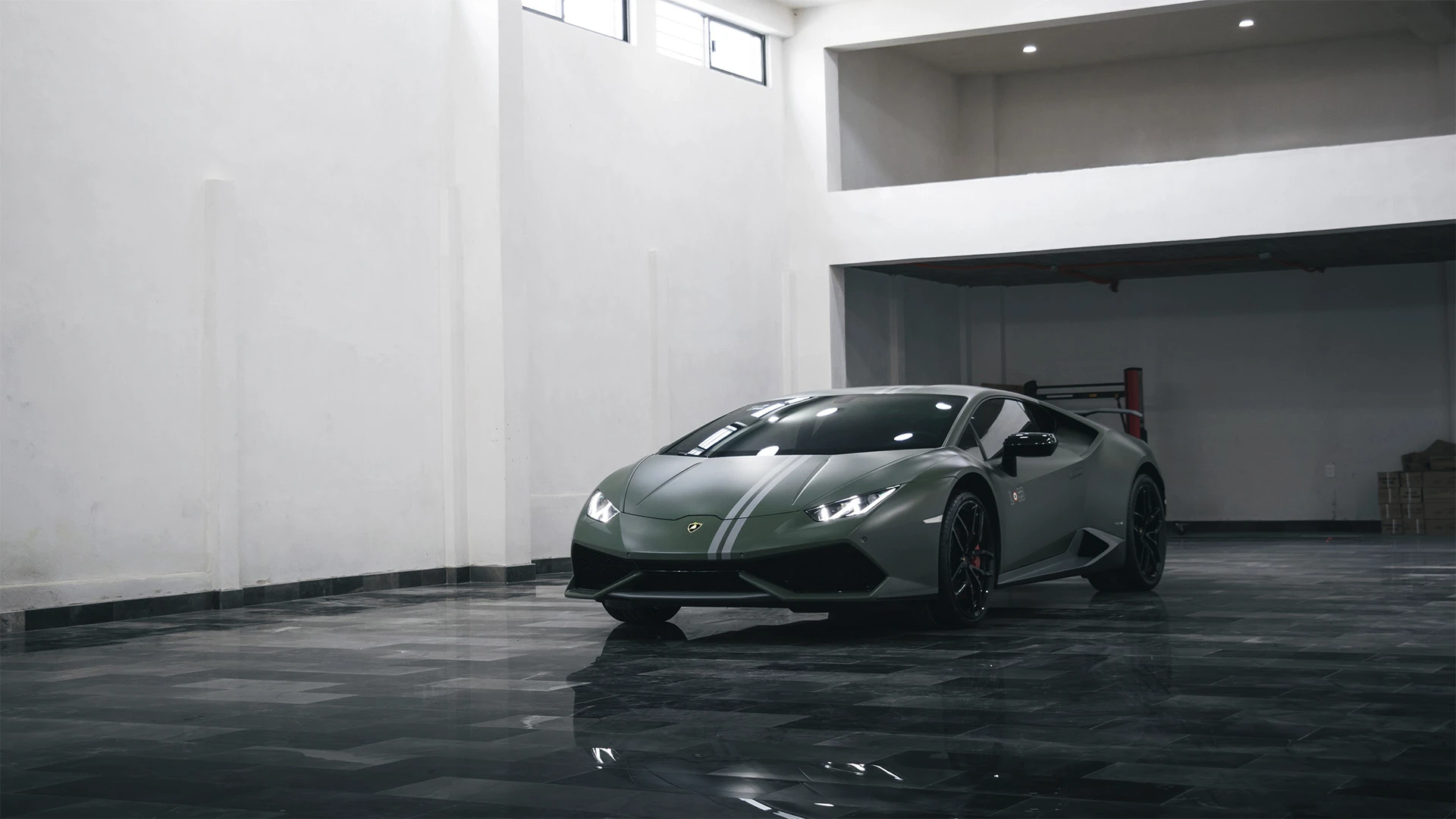 Green Lamborghini, with two white stripes, parked in a garage