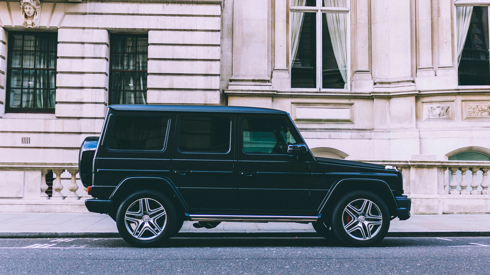 Black Mercedes G-Wagon parked on the side of the road, in front of a building