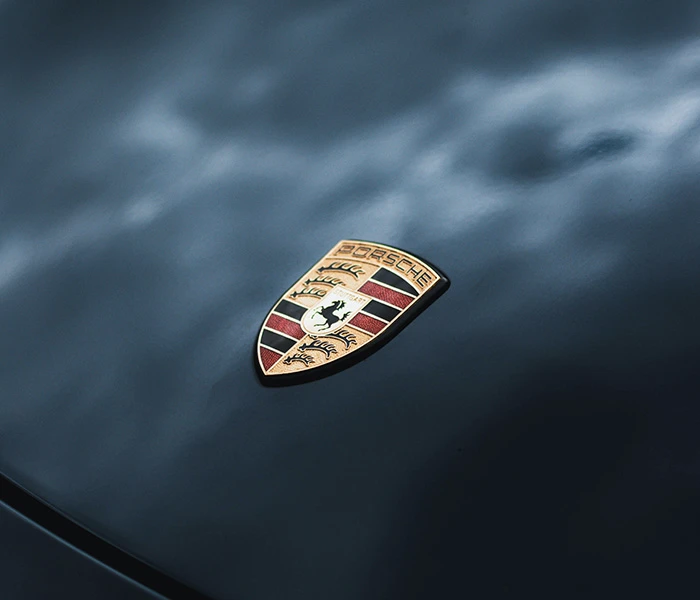 Close up of Porsche badge on the bonnet of dark Porsche