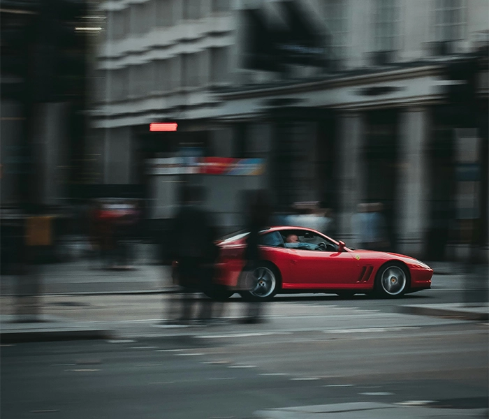 Red Ferrari in focus driving through out-of-focus city streets