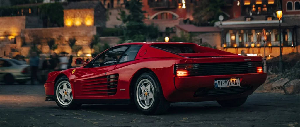 Red Ferrari Testarossa with city lights in the background